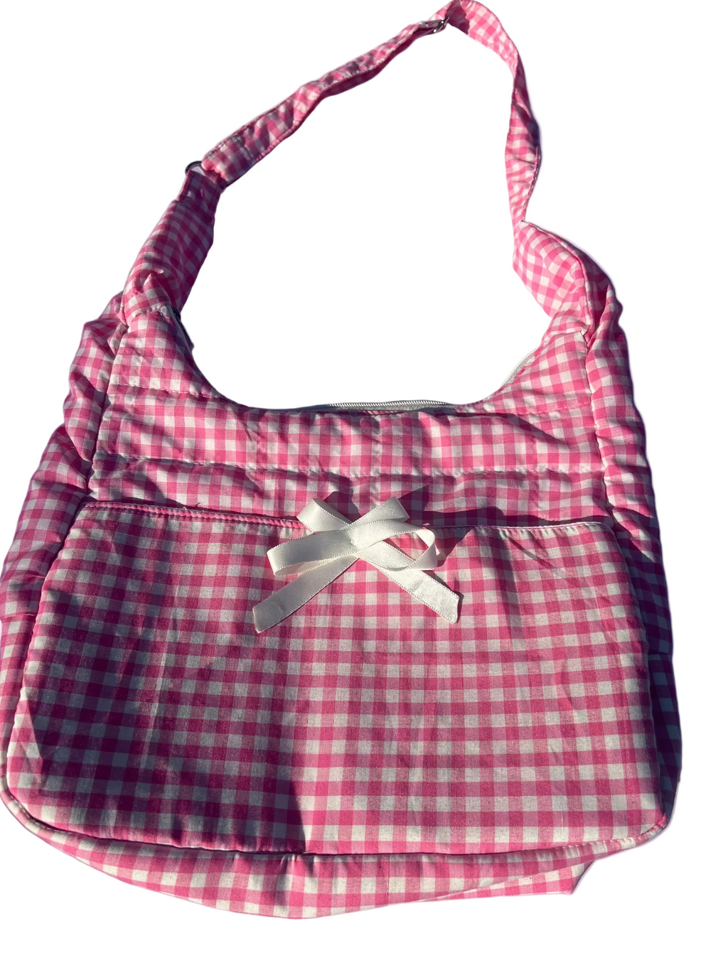 Pink and white checkered bag with a bow on a blue surface